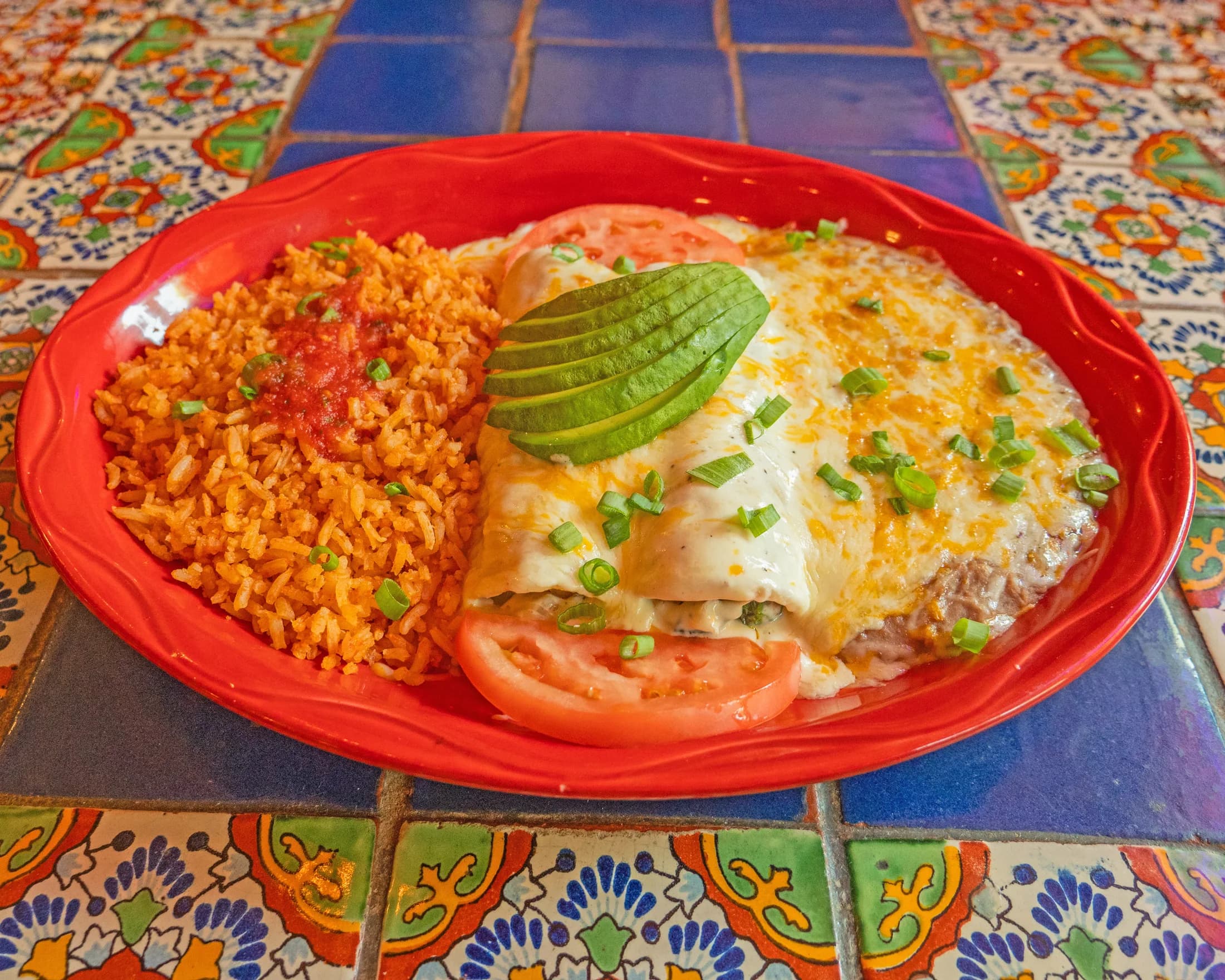 Spinach enchiladas served with rice, tomato, and avocado