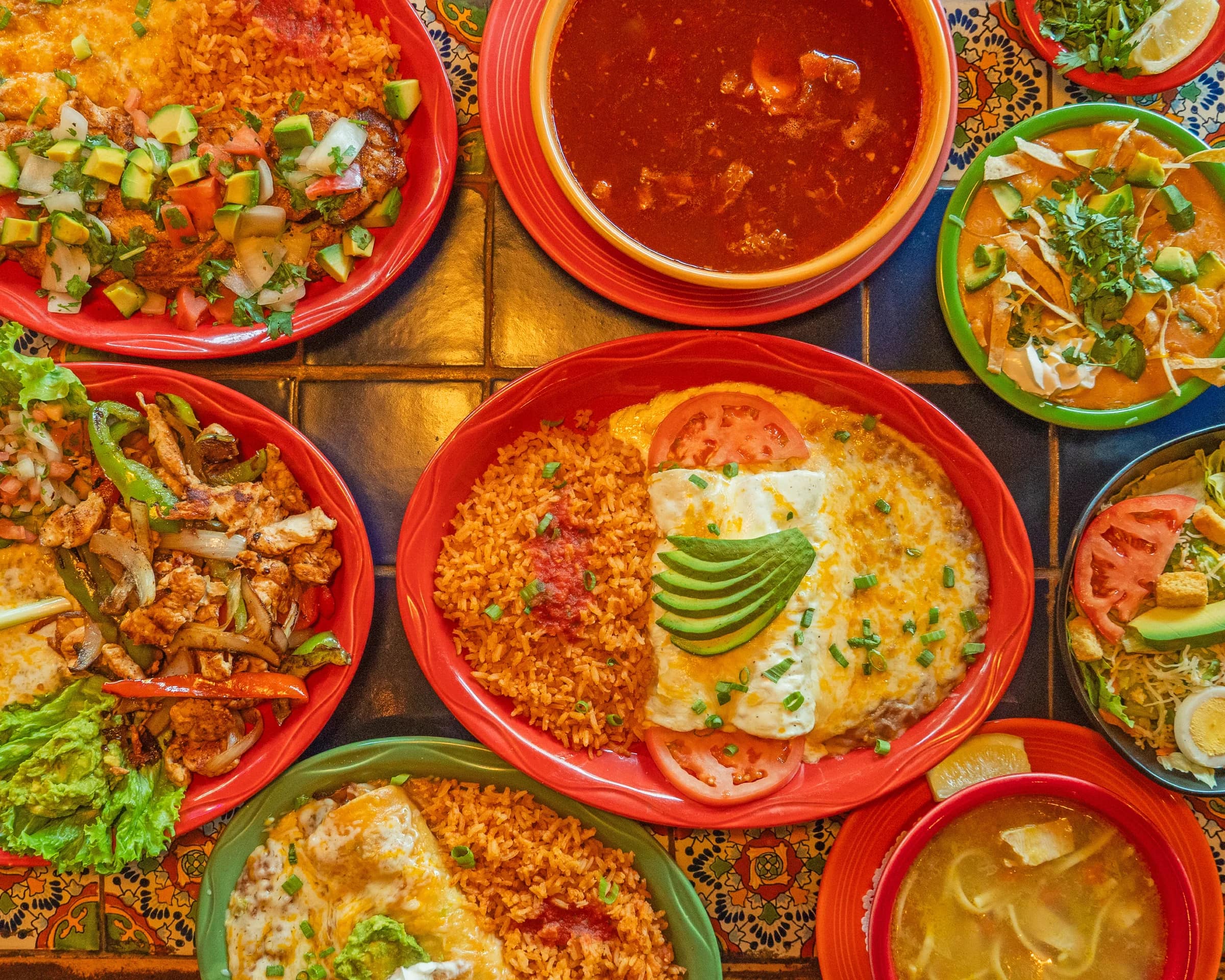 A colorful table filled with Joselito's enchiladas, fajitas, tacos, and soup